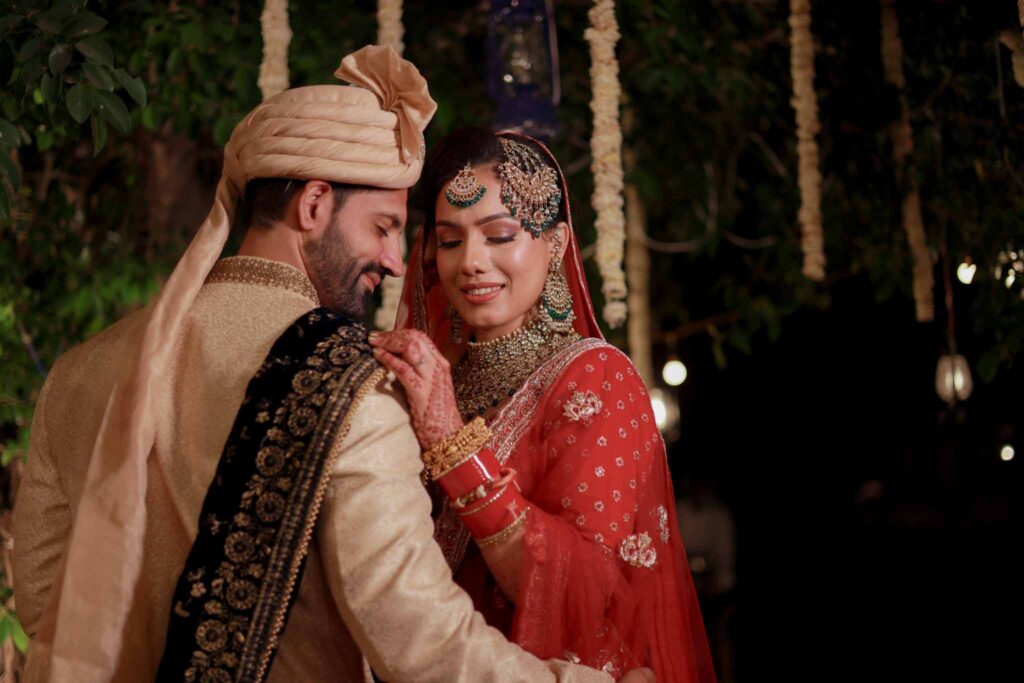 Close up view of a bride in red lehnga and a groom in white shervani