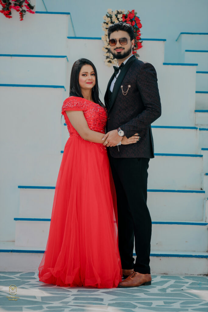 Girl in a red dress holding hands of a boy in black tuxedo