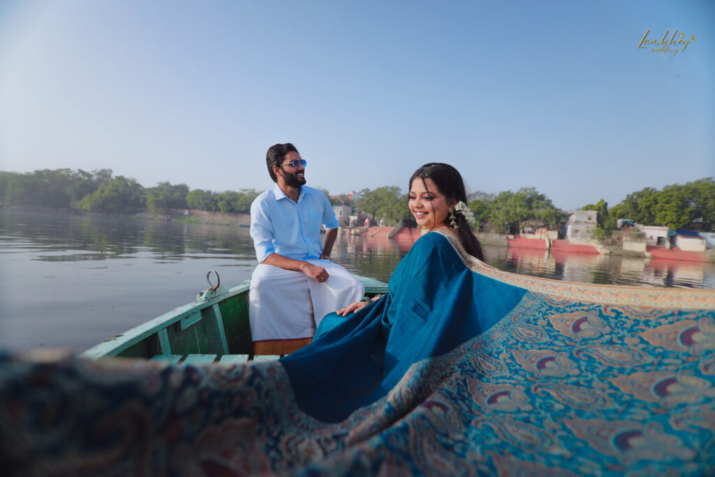 Boy in a white dhoti and girl in a blue saree sitting on a boat