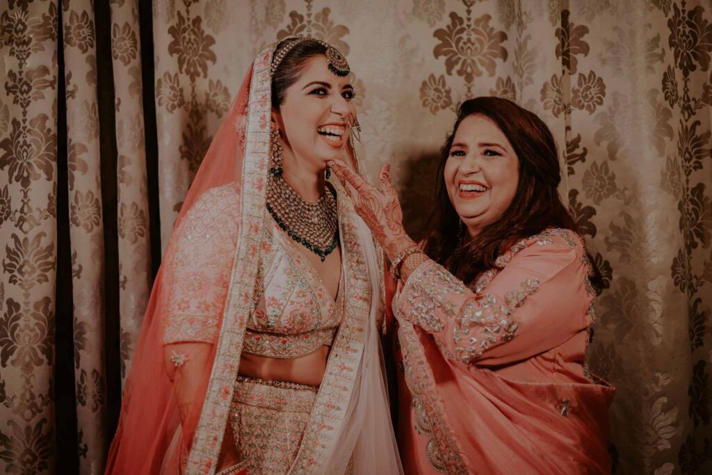 bride smiling in pink lehnga with her mother