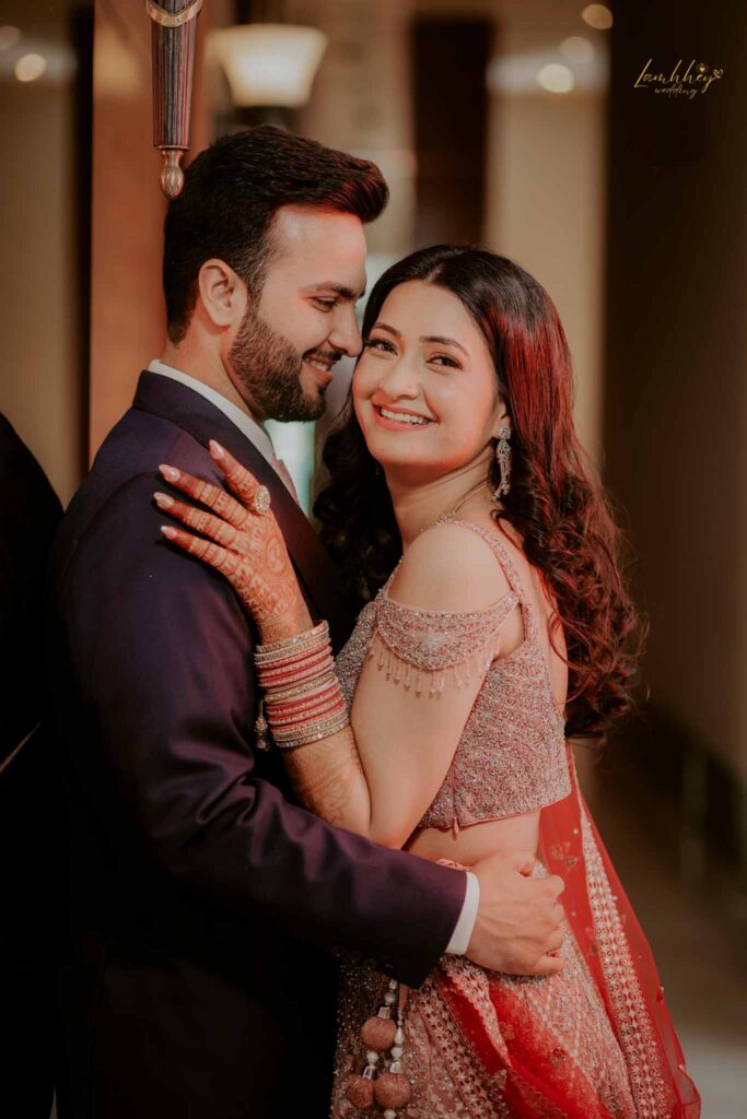 smiling bride in red lehnga and groom in black