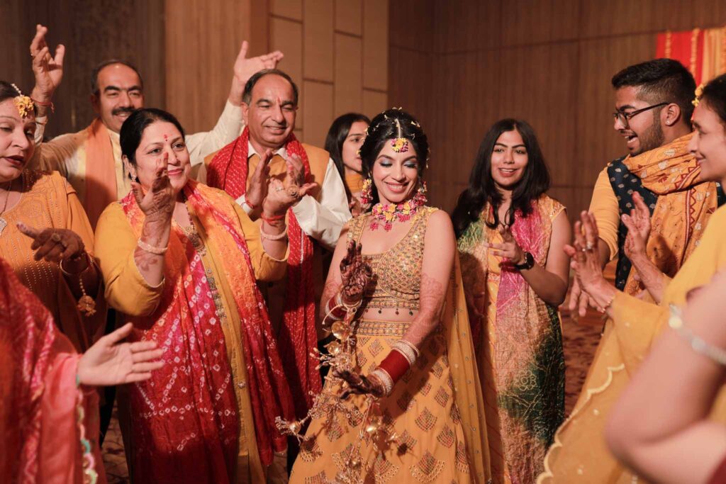 Happy bride in yellow lehnga dancing with family