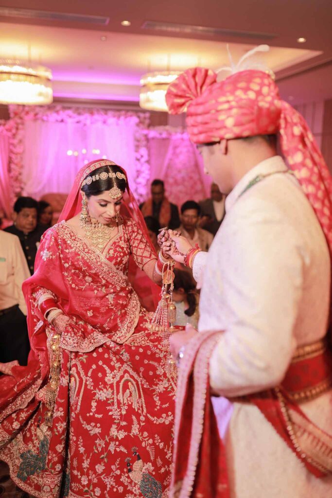Groom holding hand of a bride in red lehnga on stage