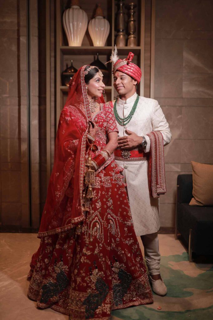 Happy bride in red lehnga and groom in cream shervani
