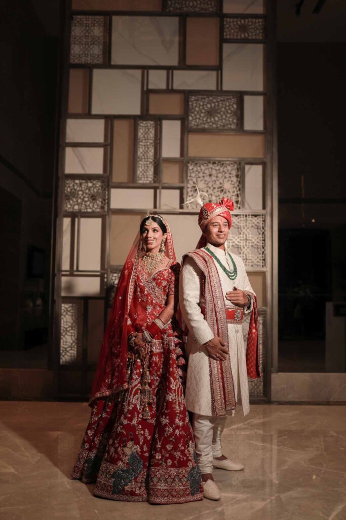 Bride in red lehnga and groom in cream shervani