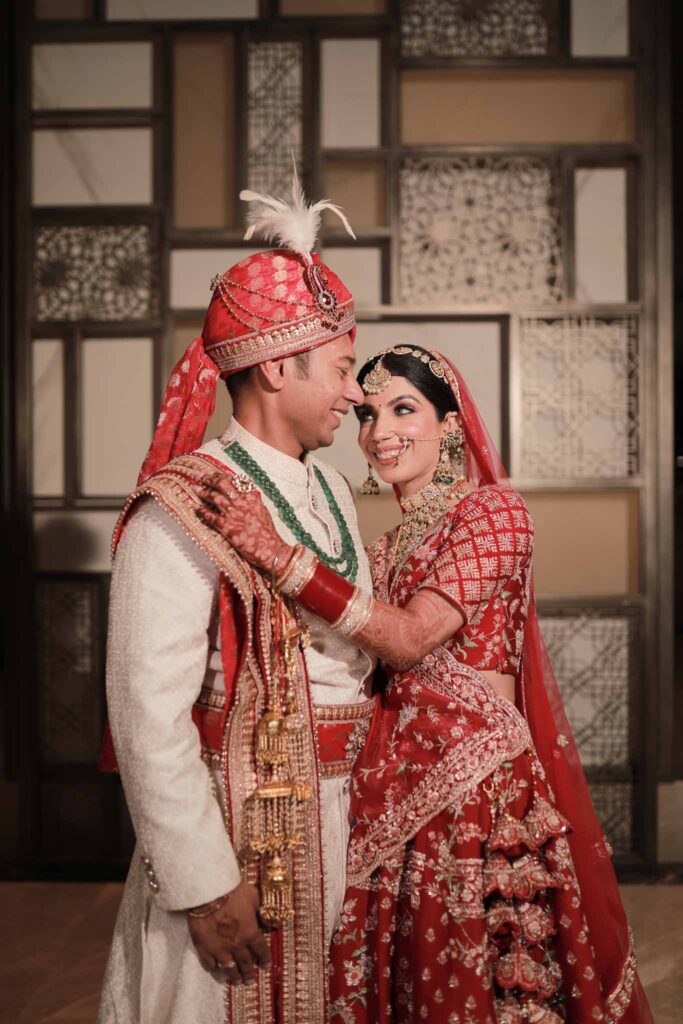Happy groom in white shervani and bride in red lehnga