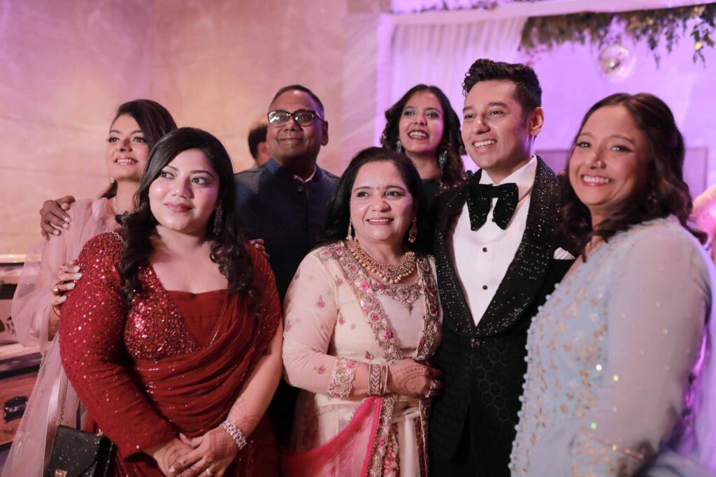Smiling groom in black suit with his family