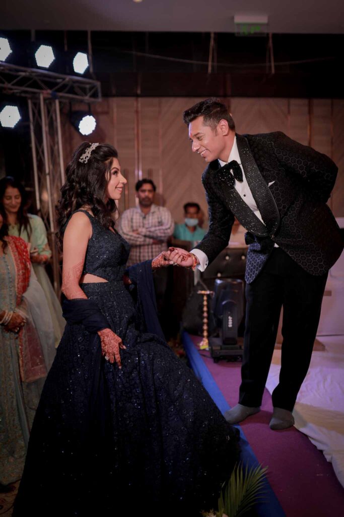 Happy bride in blue lehnga and groom in black suit holding hands